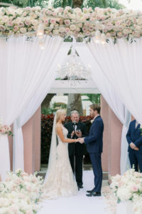 Romantic Florida Bride and Groom Exchange Vows During Outdoor Garden Wedding Ceremony, Decorated with Elegant Rose Floral Arrangements, Ivory, Blush Pink, and White Flowers Suspended Above Wedding Arch Crystal Chandelier, Bride Wearing Eve of Milady Kleinfeld Bridal Dress, Groom in Navy Suit with Champagne Rose Boutonniere | Tampa Bay Wedding Planner Parties A'La Carte | Florida Wedding Venue and Historic Resort The Vinoy Renaissance in Downtown St. Petersburg