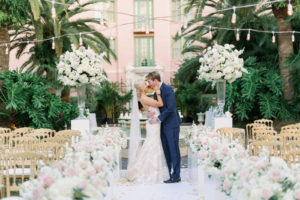 Romantic Florida Bride and Groom Kiss Intimate Embrace at Outdoor Garden Wedding Ceremony, Decorated with Elegant Tall Rose Floral Arrangements, Ivory, Blush Pink, and White Flowers, Gold Napoleon Chairs, Bride Wearing Eve of Milady Kleinfeld Bridal Dress, Groom in Navy Suit with Champagne Rose Boutonniere | Tampa Bay Wedding Planner Parties A'La Carte | Tea Garden Ceremony at Florida Wedding Venue and Historic Resort The Vinoy Renaissance in Downtown St. Petersburg