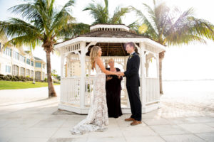 Florida Bride and Groom During Intimate Vow Exchange During Beachfront Ceremony under Gazebo, Bride Wearing Made With Love Bridal Tan Sasha Dress | Private Tampa Bay Wedding Venue Isla Del Sol Yacht and Country Club | Intimate Wedding Planner Elope Tampa Bay