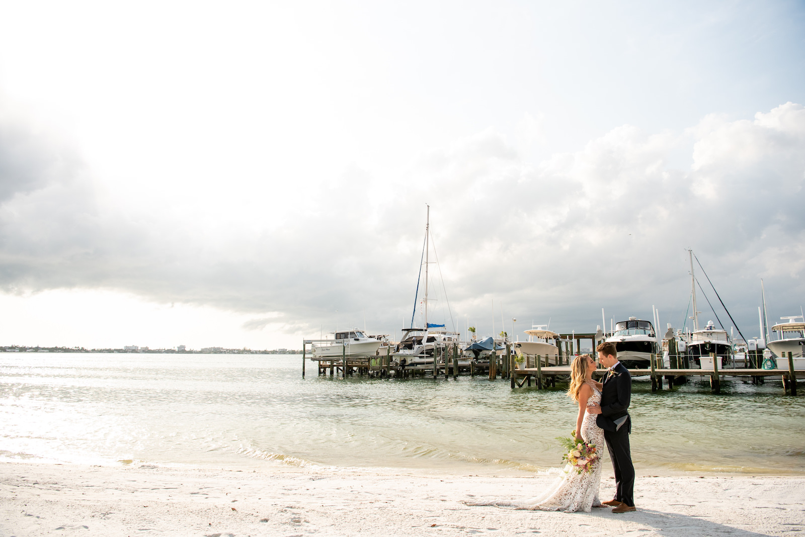 Florida Bride and Groom During Intimate Vow Exchange During Beachfront Ceremony under Gazebo, Bride Wearing Made With Love Bridal Tan Sasha Dress, Holding Whimsical Vibrant Inspired Bouquet | Private Tampa Bay Wedding Venue Isla Del Sol Yacht and Country Club | Intimate Wedding Planner Elope Tampa Bay