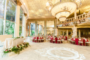 Clearwater Florida Fairy Tale Wedding Reception with Chandeliers and Monogram GOBO Dancefloor | Burgundy Deep Red Guest Table Linens with Gold Chiavari Chairs | Champagne Sweetheart Table with Loveseat and Greenery Garland with White and Burgundy Roses | Kapok Special Events