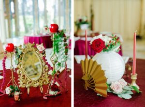 Clearwater Florida Disney Fairy Tale Wedding Reception Centerpiece Snow White Gold Mirror with Red Apples Amaranthus and Greenery | Mulan Centerpiece with Japanese Hand Fan and Paper Lantern with Red and Pink Roses and Hypericum Berries and Red Taper Candles in Gold Candlesticks
