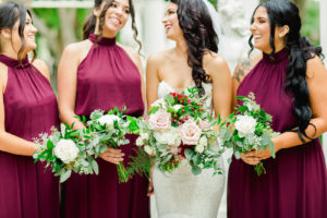 Outdoor Bridal Party Portrait | Mermaid Fitted Lace Sweetheart Wedding Gown with Tulle Skirt and Sheer Illusion Panels with Long Cathedral Veil from Tampa Dress Shop Isabel Oneil Bridal Collection | Deep Red Burgundy and Blush Pink Rose Bouquet | Long Burgundy Deep Red Chiffon Bridesmaid Dresses by JJ's House from Tampa Dress Shop Nikki's Glitz & Glam Boutique