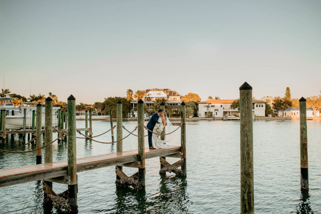 Romantic Intimate Bride and Groom on Waterfront Dock Kissing, Bride Holding Lush White, Ivory and Blush Pink Roses and Eucalyptus Floral Bouquet | St. Pete Boutique Hotel Wedding Venue Hotel Zamora