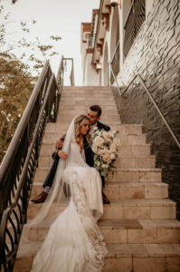 Romantic Intimate Bride and Groom on Stairs, Bride Holding Lush White, Ivory and Blush Pink Roses and Eucalyptus Floral Bouquet Wearing Lace and Illusion Wedding Dress and Full Length Veil | St. Pete Boutique Hotel Wedding Venue Hotel Zamora