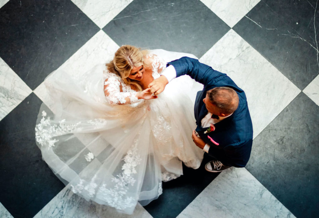 Intimate Portrait of Bride Tampa Bay Wedding Planner Katy from Coastal Coordinating and Groom Twirling New Wife on Black and White Checkered Floor | Wedding DJ Grant Hemond and Associates