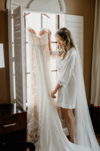 St. Pete Bride Getting Ready Wedding Portrait Admiring Romantic Lace and Illusion Wedding Dress with Cape