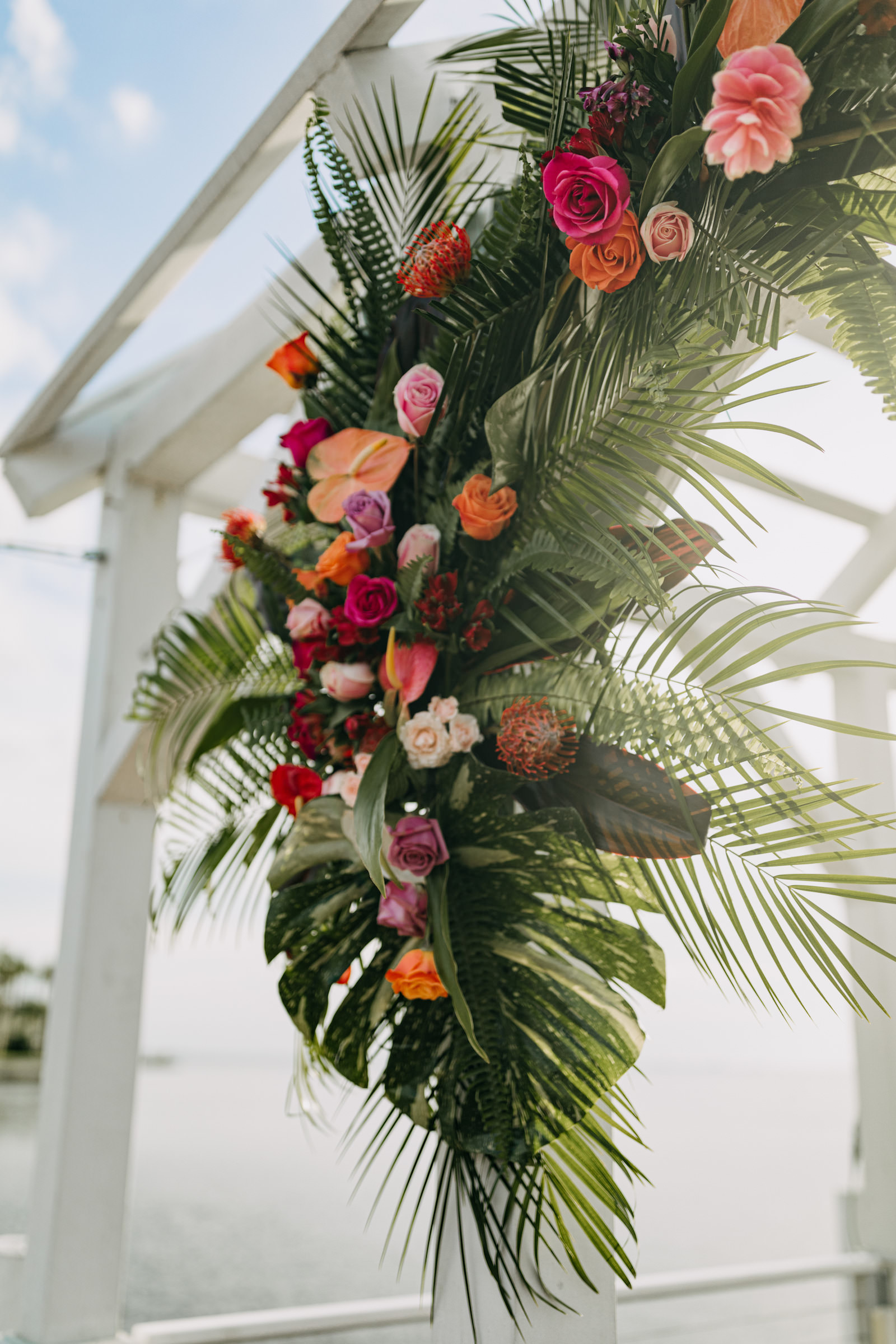 Tropical Colorful Wedding Floral Arrangement, Monstera Leaves, Palm Tree Leaves, Red, Orange and Pink Roses | Tampa Bay Wedding Florist Brides N Blooms | Wedding Planner Elope Tampa Bay | Amber McWhorter Photography | Styled Shoot