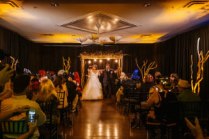 Halloween Bride and Groom Wedding Ceremony Recessional, Black Linen Draping, Wooden Branches Arch | Tampa Bay Wedding Planner UNIQUE Weddings and Events | Wedding Rentals A Chair Affair and Wedding Linens Over the Top Rental Linens | Wedding Dress Truly Forever Bridal