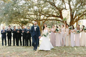 Classic Bride in Fit and Flare Strapless Dress, Groom in Tuxedo, Groomsmen and Bridesmaids in Mix and Match Neutral Taupe Dresses Holding Tropical White Floral Bouquets | Tampa Bay Wedding Florist and Designer John Campbell Weddings