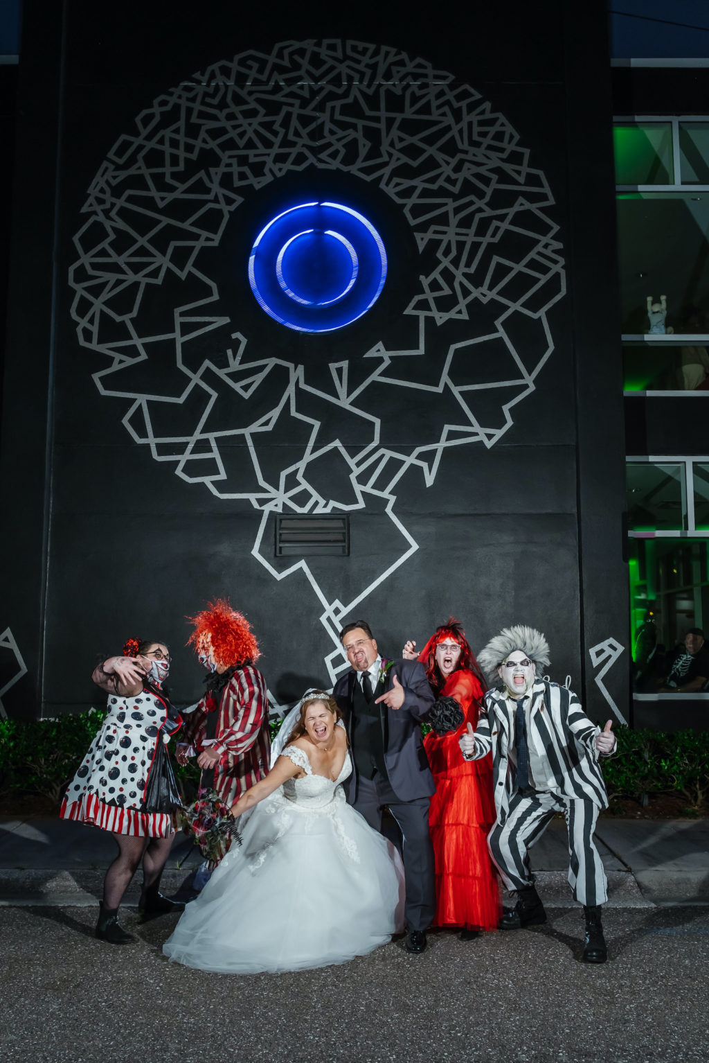 Halloween Wedding Bride and Groom and Guests in Costumes Outside Black Whimsical Wall Mural in Downtown St. Pete