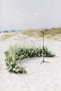 Romantic Classic Wedding Ceremony beachfront decor, tall white flowers and greenery half circle wreath on sand | Clearwater wedding planner Parties A'la Carte