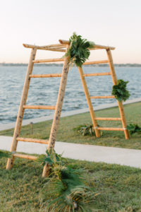 Tropical Modern Waterfront Wedding Ceremony Decor, Bamboo Ladder Arch with Monstera Palm Tree Leaf Arrangements | Tampa Bay Wedding Planner, Florist and Designer John Campbell Weddings