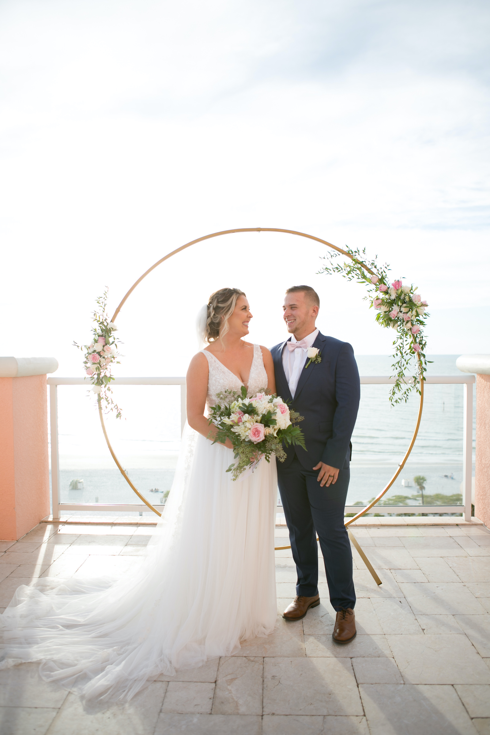 Bride and Groom Exchanging Wedding Vows During Ceremony, Modern Elegant Gold Circular Arch with Pink and Ivory Florals, Greenery | Tampa Bay Wedding Photographer Carrie Wildes | Wedding Hair and Makeup Femme Akoi Beauty Studio | Wedding Dress Truly Forever Bridal | Wedding Planner Coastal Coordinating | Wedding Rentals Outside the Box | Wedding Florist Brides N Blooms