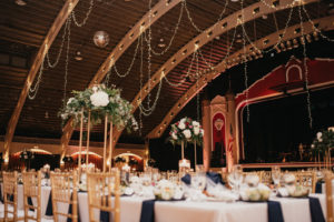 Traditional romantic wedding reception decor, hanging draped lights, gold chiavari chairs, tall floral centerpieces navy blue linens | Tampa Bay wedding planner Special Moments Events | Wedding Venue St. Pete Coliseum