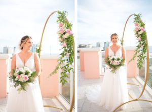 Elegant Modern Wedding Ceremony Decor, Gold Circular Arch with Greenery and Ivory and Pink Floral Arrangements, Bride Wearing Flowy Lace and Tulle V Neckline Wedding Dress Holding A Lush Floral Bouquet | Tampa Bay Wedding Photographer Carrie Wildes | Wedding Planner Carrie Wildes | Waterfront Hotel Balcony Clearwater Beach Hyatt Regency Clearwater Beach | Wedding Florist Brides N Blooms | Wedding Hair and Makeup Femme Akoi Beauty Studio | Wedding Rentals Outside the Box | Wedding Planner Coastal Coordinating