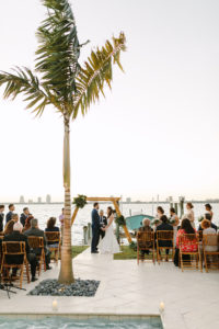 Modern Tropical Waterfront Bride and Groom Exchanging Wedding Vows Under Bamboo Ladder Arch, Waterfront Ceremony | Tampa Bay Wedding Planner, Florist and Designer John Campbell Weddings