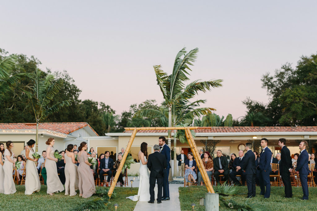 Modern Tropical Waterfront Bride and Groom Exchanging Wedding Vows Under Bamboo Ladder Arch, Waterfront Ceremony | Tampa Bay Wedding Planner, Florist and Designer John Campbell Weddings