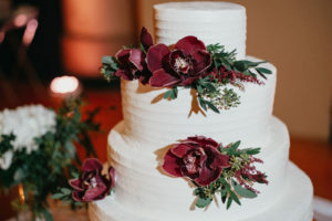 White wedding cake with dark red flowers