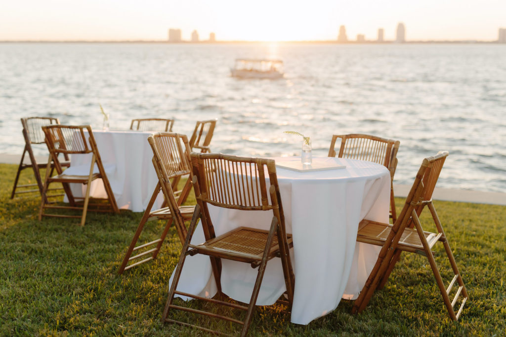 Modern Tropical Waterfront Wedding Reception Decor, Bamboo Wooden Chairs, White Linen Round Tables, Minimal Centerpieces | Tampa Bay Wedding Planner, Florist and Designer John Campbell Weddings