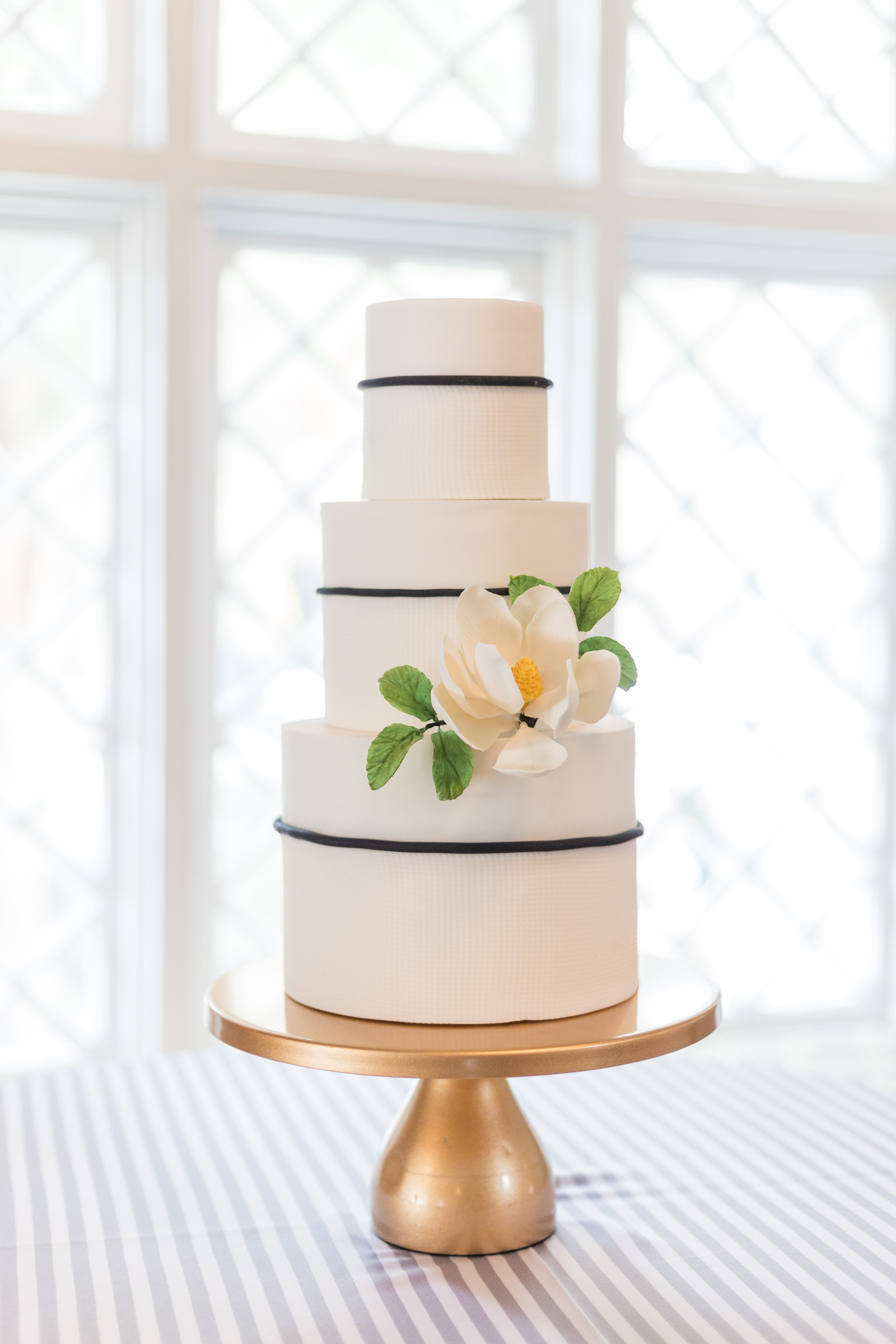 Classic three tier white and blue wedding cake with flower on table with blue striped tablecloth | Tampa Bay wedding planner Elegant Affairs by Design | Tampa Bay Cake Company