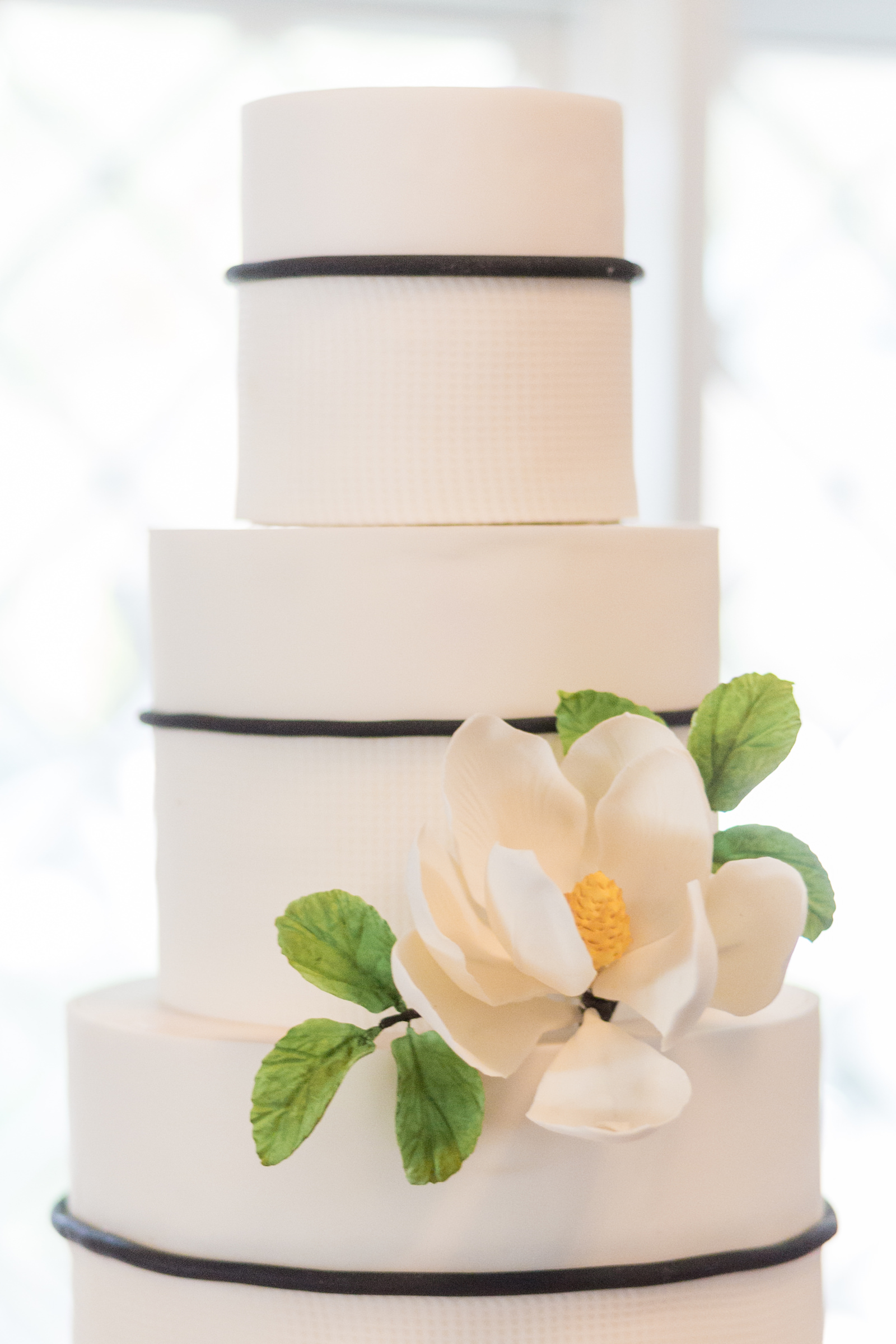 Classic three tier white and blue wedding cake with flower on table with blue striped tablecloth | Tampa Bay wedding planner Elegant Affairs by Design | Tampa Bay Cake Company