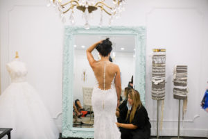 Tampa Bay bride getting fitted at boutique bridal shop Isabel O'Neil in wedding dress, open illusion back with buttons and lace