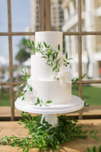 Garden-style three tier smooth wedding cake with greenery and white flowers