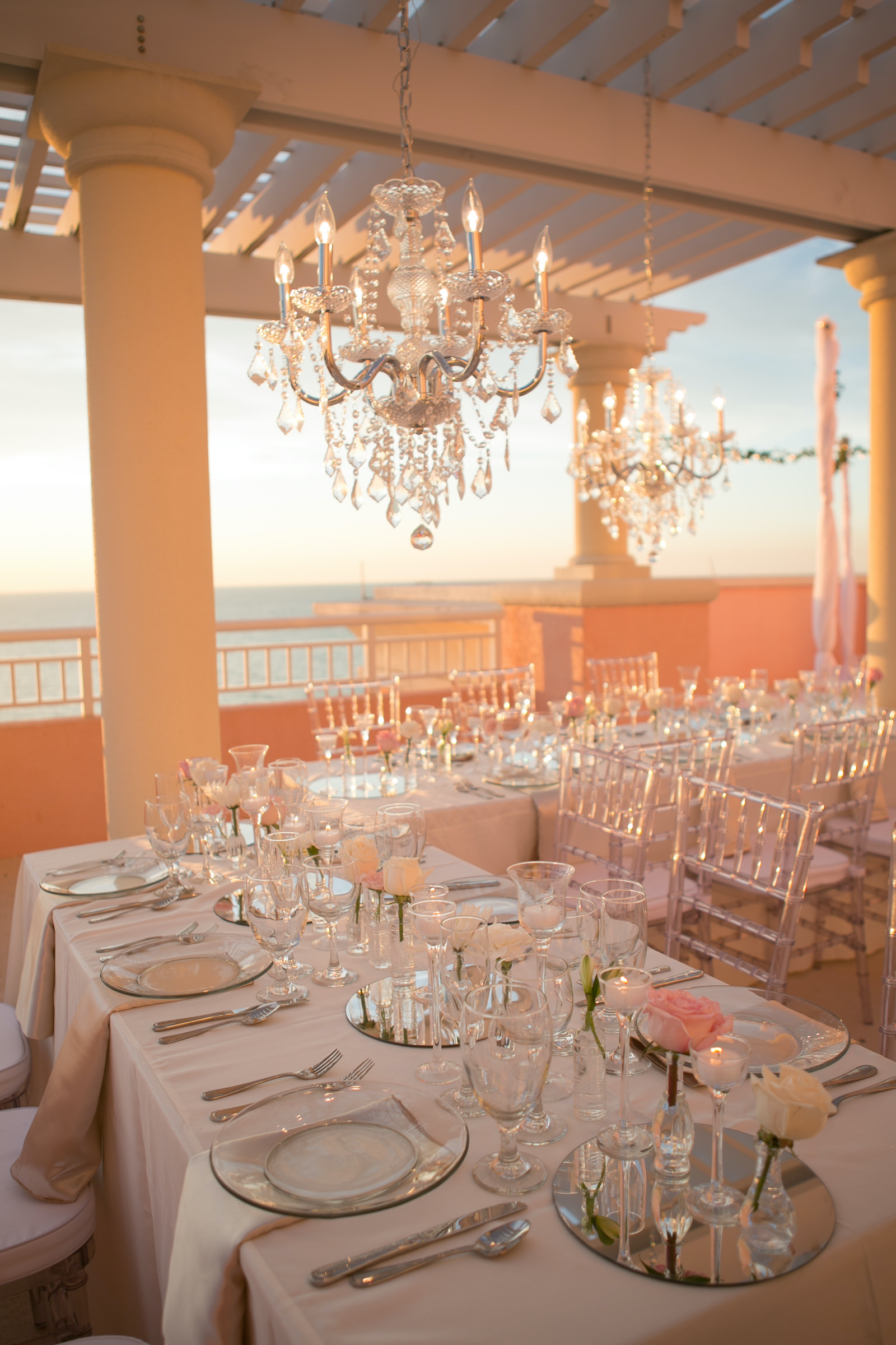 Elegant Modern Wedding Reception Decor on Rooftop Balcony of Waterfront Wedding Venue Hyatt Regency Clearwater Beach, Long Tables with Acrylic Chiavari Chairs, Hanging Crystal Chandeliers | Tampa Bay Wedding Photographer Carrie Wildes | Wedding Planner Coastal Coordinating | Wedding Rentals Outside the Box