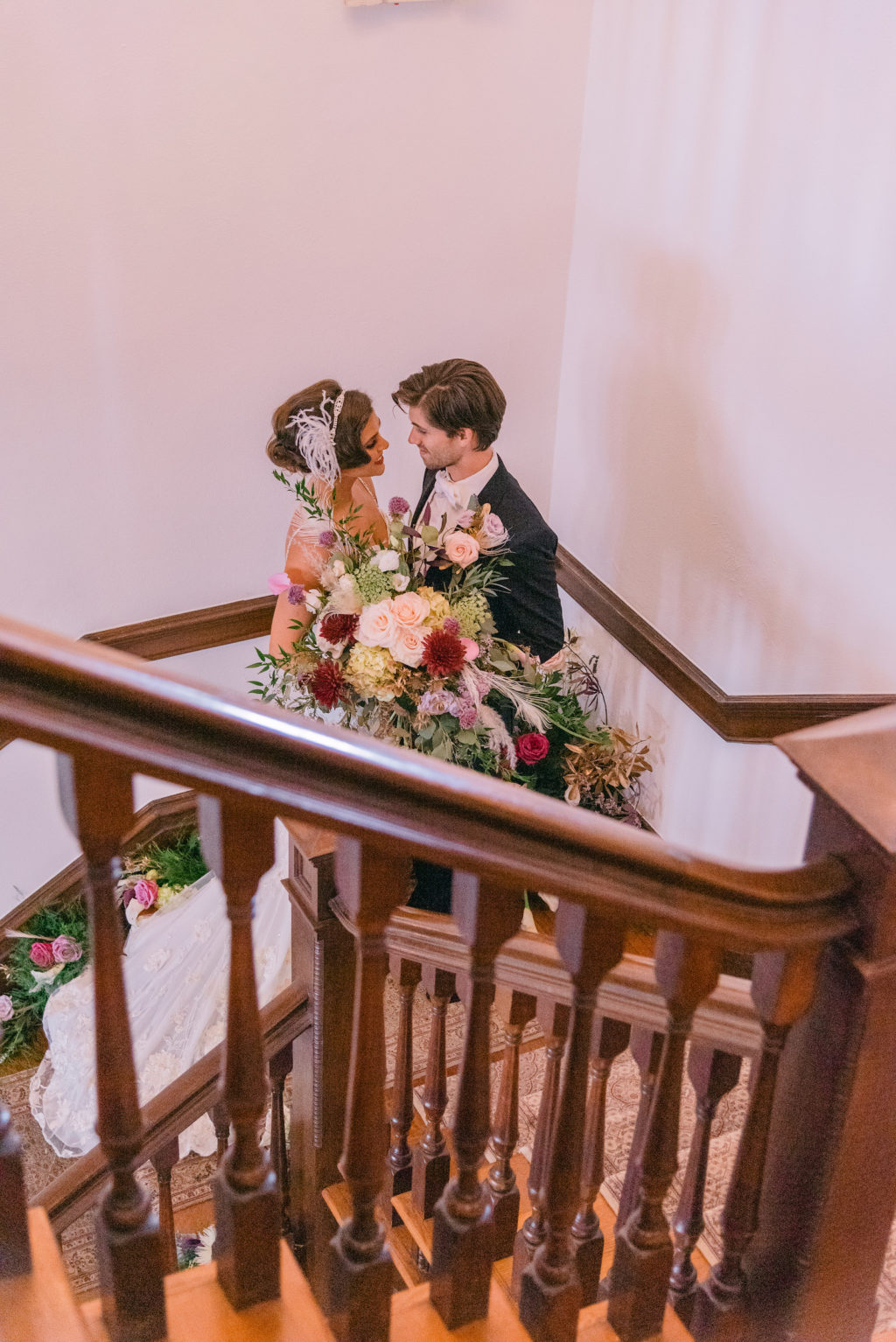 Romantic Bride and Groom Photo on Staircase Holding Whimsical Lush Jewel Toned Floral Bouquet | Tampa Bay Wedding Planner EventFull Weddings