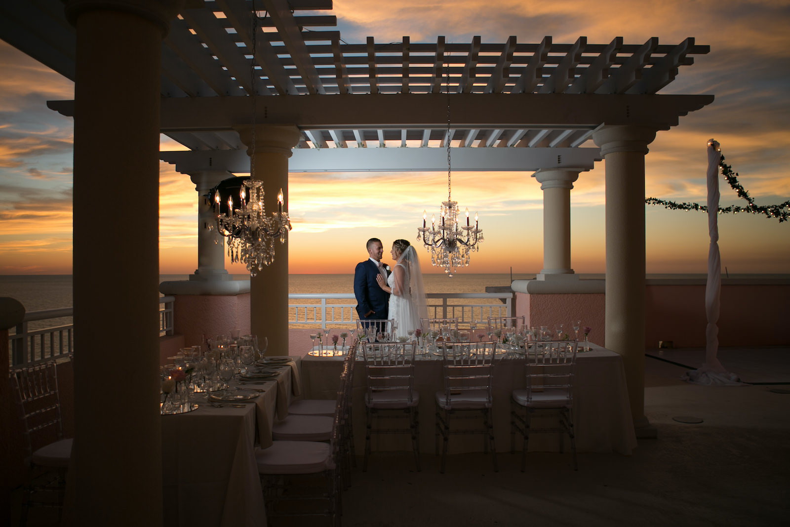 Elegant Modern Wedding Reception Decor on Rooftop Balcony of Waterfront Wedding Venue Hyatt Regency Clearwater Beach, Long Tables with Acrylic Chiavari Chairs, Hanging Crystal Chandeliers | Tampa Bay Wedding Photographer Carrie Wildes | Wedding Planner Coastal Coordinating | Wedding Rentals Outside the Box