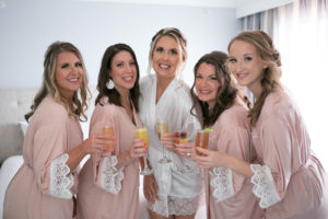 Tampa Brides and Bridesmaids in Blush Pink Robes Cheering with Mimosas | Clearwater Beach Wedding Photographer Carrie Wildes | Wedding Hair and Makeup Femme Akoi