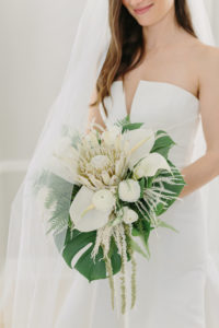 Tampa Bay Bride Holding Tropical Floral Bouquet with Monstera Palm Leaf, White Orchid, Roses, King Protea and Hanging Amaranthus | Wedding Florist and Designer John Campbell Weddings