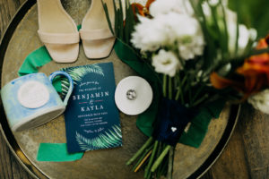 Navy Blue and Green Clearwater Tropical Wedding Invitation with Palm Frond Leaf | Wedding Ring Shot Flat Lay with Bridal Accessories Bouquet and Shoes | Amber McWhorter Photography