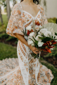 Boho Gold Bronze Embroidered Overlay Wedding Dress Bridal Gown with Illusion Sleeves and Train | Tropical Boho Bridal Bouquet with White Roses Orange Orchids and Palm Frond Leaves | Amber McWhorter Photography