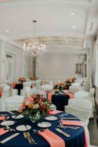 Indoor Clearwater Wedding Reception at Historic Venue Hotel | Navy Blue Reception Table with Coral Peach Pink Napkins and Tropical Floral Arrangement Centerpieces