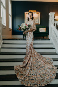 Indoor Bridal Portrait on Staircase | Boho Gold Bronze Embroidered Overlay Wedding Dress Bridal Gown with Illusion Sleeves and Train | Tropical Boho Bridal Bouquet | Amber McWhorter Photography