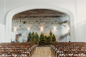 Indoor Tampa Christmas Wedding Ceremony with Wood Cross Back Chairs and Lit Christmas Tree Backdrop