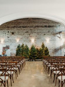 Indoor Tampa Christmas Wedding Ceremony with Wood Cross Back Chairs and Lit Christmas Tree Backdrop