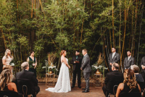 Modern Tropical Inspired Florida Wedding Ceremony in Bamboo Garden, DIY Floral Centerpieces with Bronze Base and Greenery, Bride and Groom Exchanging Vows During Outdoor Ceremony | Downtown St. Pete Historic Wedding Venue NOVA 535 - Courtyard