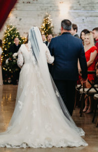 Bride Walking Down Aisle with Father during Indoor Christmas Tampa Wedding | Long Sleeve Lace Plunging V Neck Tulle Ballgown Wedding Dress Bridal Gown with Long Cathedral Veil