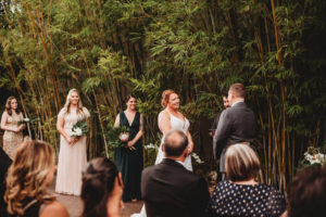 Modern Tropical Inspired Florida Wedding Ceremony in Bamboo Garden, DIY Floral Centerpieces with Bronze Base and Greenery, Bride and Groom Exchanging Vows During Outdoor Ceremony | Downtown St. Pete Historic Wedding Venue NOVA 535 - Courtyard