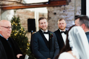 Groom Seeing His Bride for the First Time | Groom Wearing Navy Blue Jacket with Black Satin Lapel and Bow Tie | Tampa Christmas Wedding