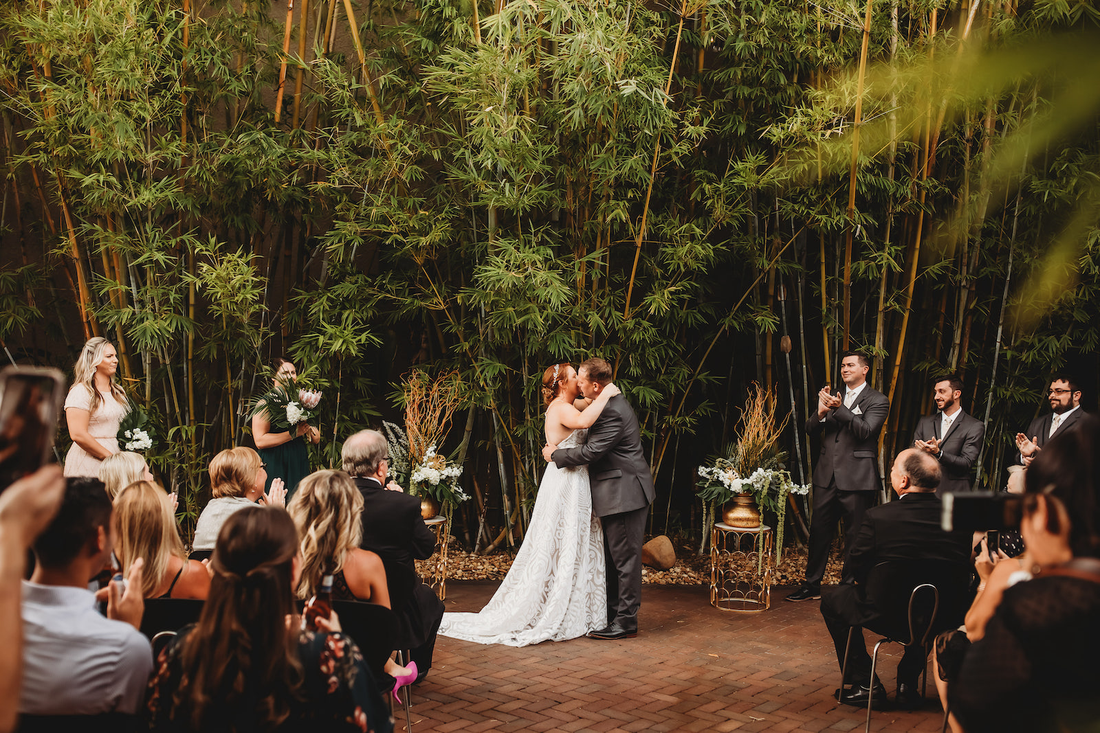 Modern Tropical Inspired Florida Wedding Ceremony in Bamboo Garden, DIY Floral Centerpieces with Bronze Base and Greenery, Bride and Groom Exchanging First Kiss During Outdoor Ceremony | Downtown St. Pete Historic Wedding Venue NOVA 535 - Courtyard