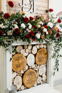 Tampa Christmas Wedding Escort Seating Chart Assignment Fireplace Mantle Monogram with Floral Arrangement of Red White and Gold Cafe au Lait Roses and Winter Greenery and Berries