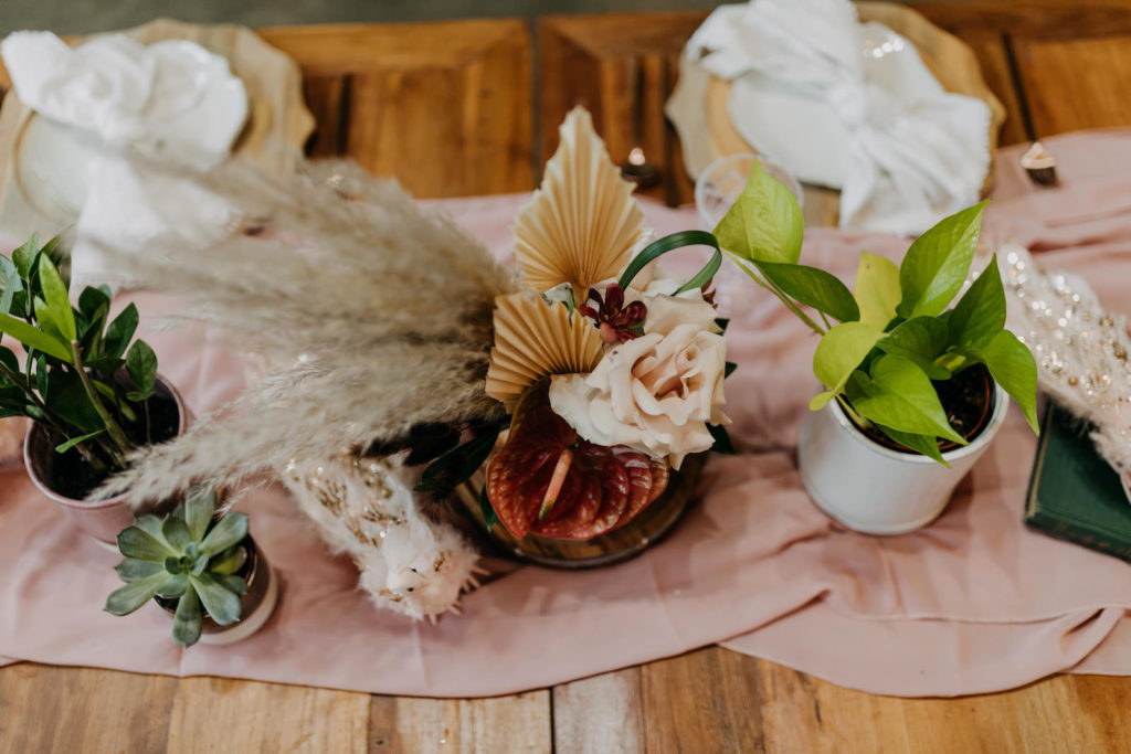 Boho Styled Shoot Decor | Unique Floral Centerpiece, Pampas Grass, Dried Flowers, Ivory Roses, Pink Anthurium, Greenery Plants, Blush Pink Table Runner, White Peacock Statue Decorations | Wedding Planner Elope Tampa Bay | Amber McWhorter Photography