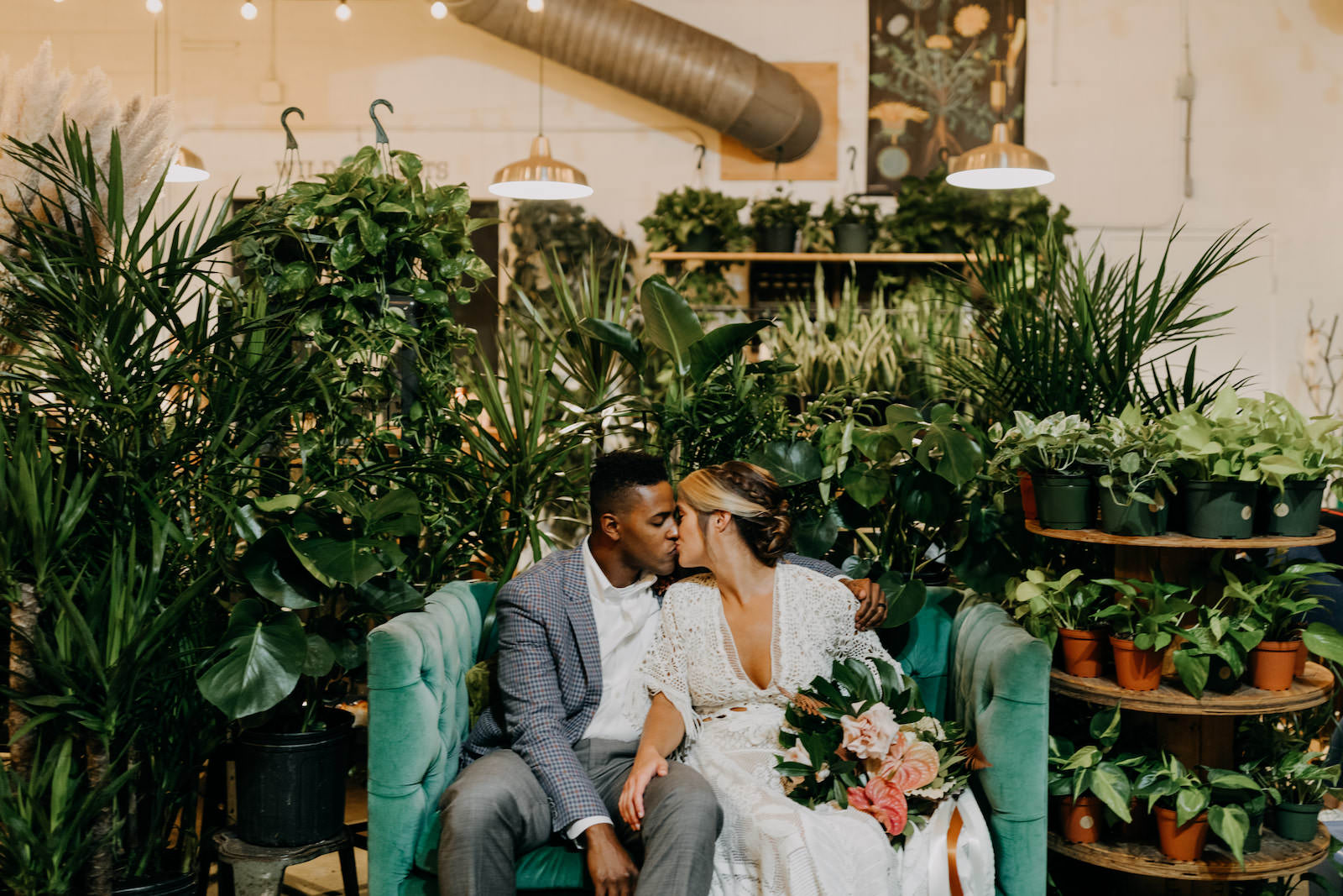 Boho Neutral Styled Shoot | Bride in Vintage Lace Fringe Short Sleeve V Neckline Wedding Dress Holding Tropical Inspired Floral Bouquet with Monstera Palm Leaf, Pink Anthurium Ivory Roses, Groom in Blue Plaid Suit with Greenery Plants | Unique St. Pete Wedding Venue Wild Roots Nursery | Amber McWhorter Photography
