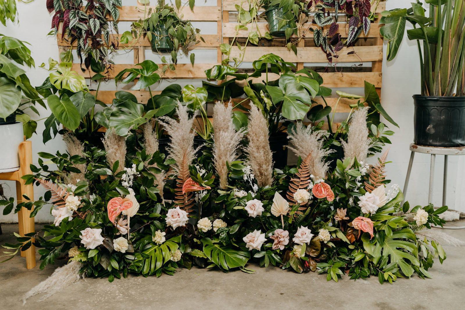 Boho Neutral Styled Shoot Decor | Wooden Pallets with Hanging Greenery Plants, Monstera Palm Trees, Floral Arrangements with Pampas Grass, Ivory Roses, Pink Anthurium | St. Pete Wedding Venue Wild Roots | Amber McWhorter Photography | Wedding Planner Elope Tampa Bay