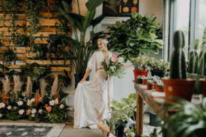 Boho Neutral Styled Shoot | Bohemian Bride in Vintage Lace, Illusion, Fringe Short Sleeve Wedding Dress Holding Tropical Inspired Floral Bouquet with Palm Tree Leaves, Ivory Flowers and Pink Anthurium | St. Pete Wedding Venue Wild Roots Nursery | Wedding Planner Elope Tampa Bay | Amber McWhorter Photography
