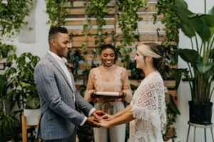 Boho Neutral Styled Shoot | Bohemian Bride in Vintage Lace and Fringe Short Sleeve Wedding Dress, Groom in Gray Plaid Suit Exchanging Vows | Unique St. Pete Wedding Venue Wild Roots Nursery | Wedding Planner Elope Tampa Bay | Amber McWhorter Photography